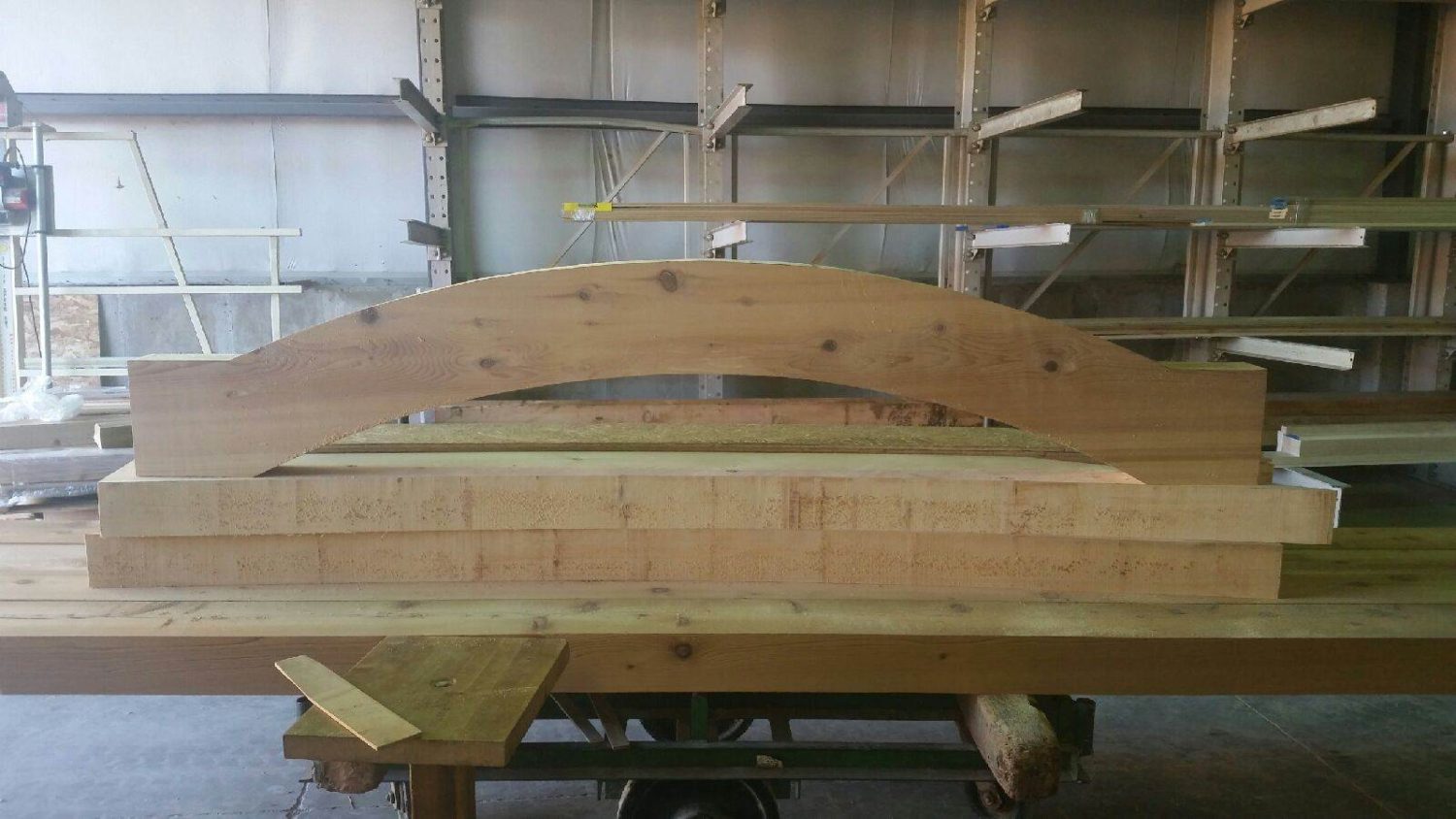 Wooden arch beam clamped for woodworking in a workshop.