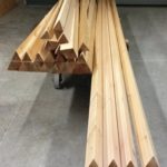 Stack of wooden triangular rods arranged on a surface.