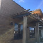 Wooden pergola outside a building under a clear blue sky.