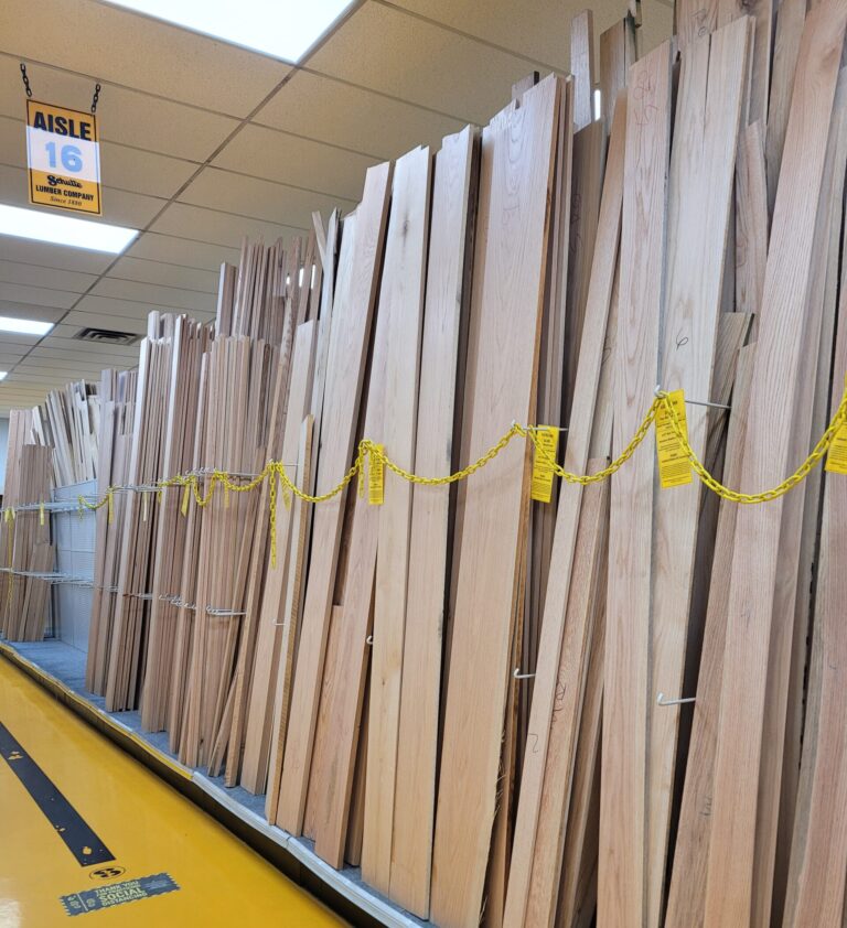 Stacks of wooden planks neatly arranged in a warehouse aisle.