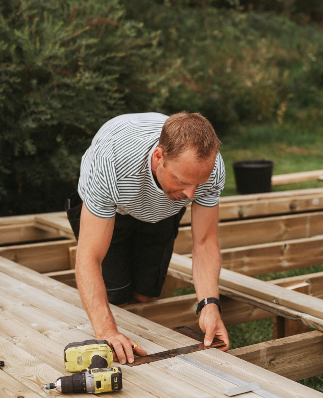Man measuring wooden boards outdoors