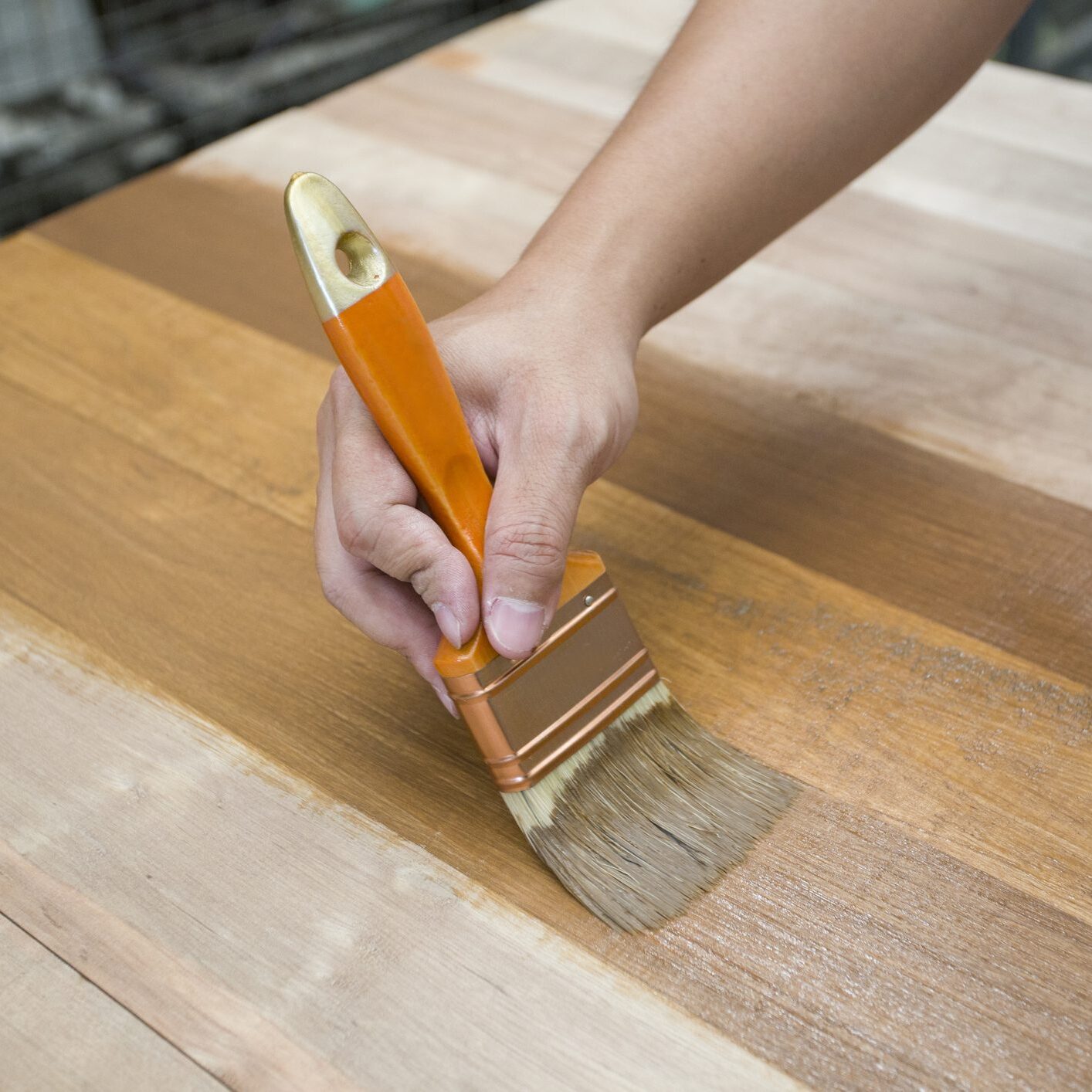 Hand applying varnish on wooden surface